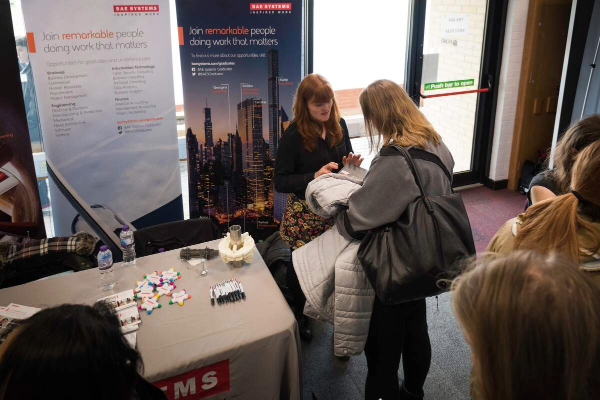 A person representing an employer speaks to a student at a stand